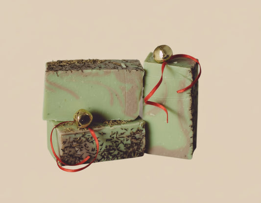 Three green soap bars with red ribbons on a beige background