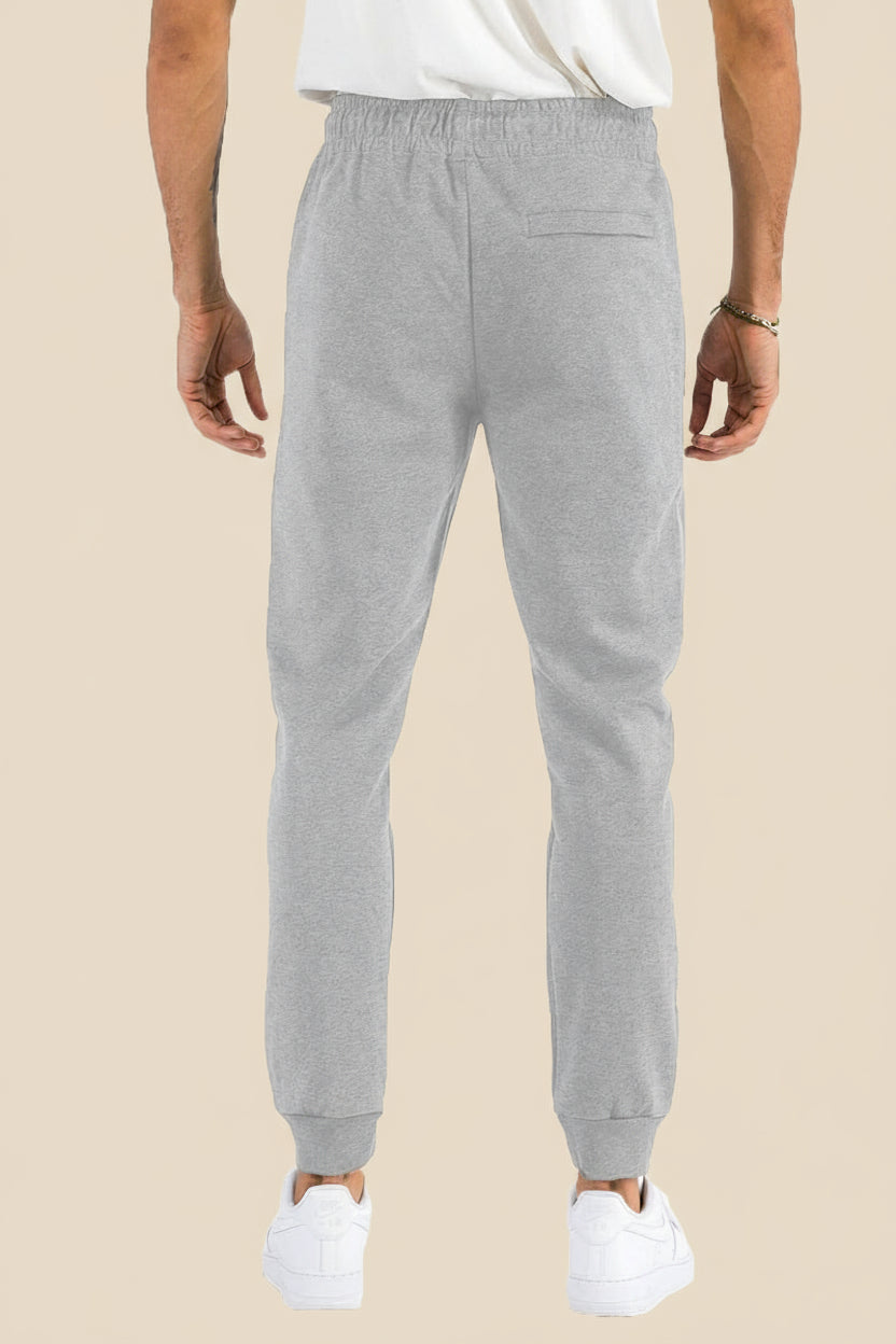 Gray sweatpants worn by a person on a tan
background