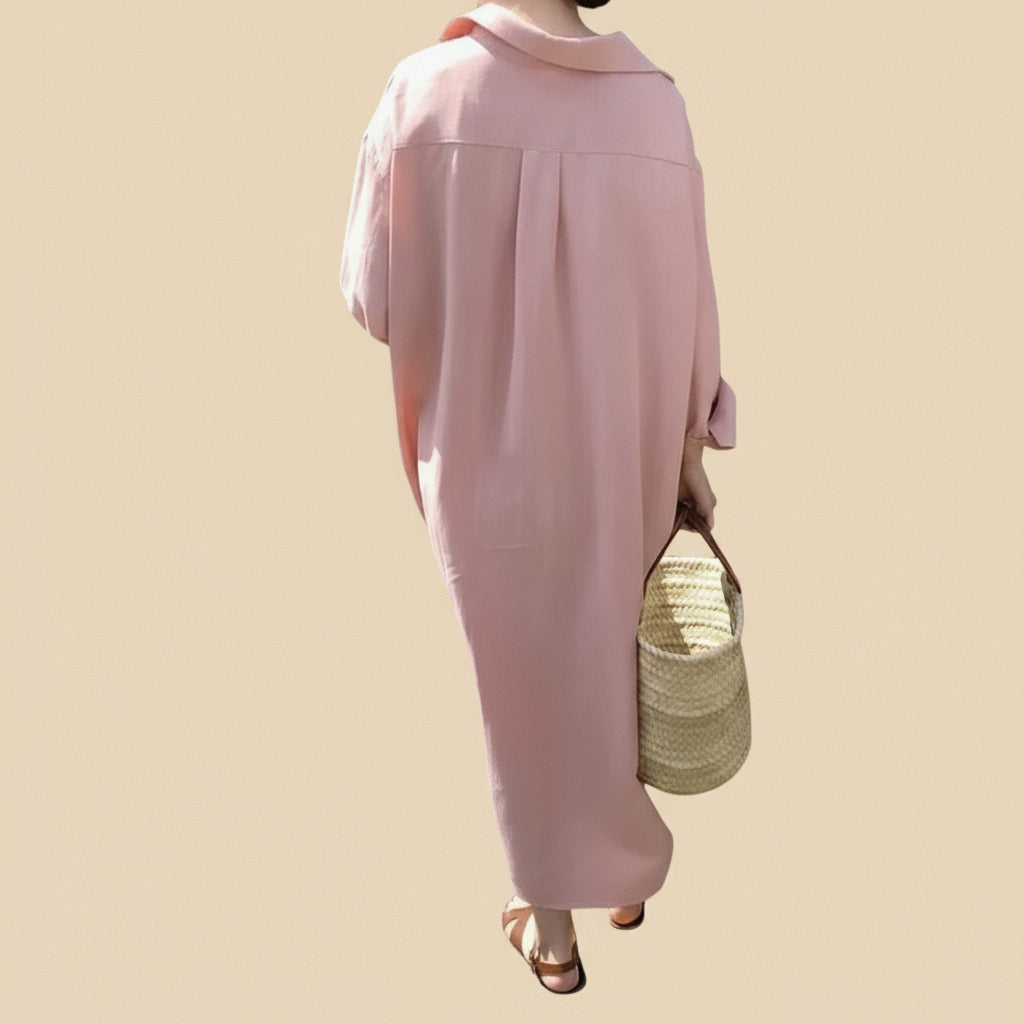 Person wearing a pink outfit holding a straw bag in front of beige backround