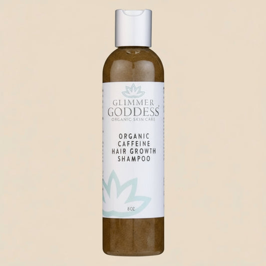Glimmer Goddess organic caffeine hair growth shampoo bottle on a tan background