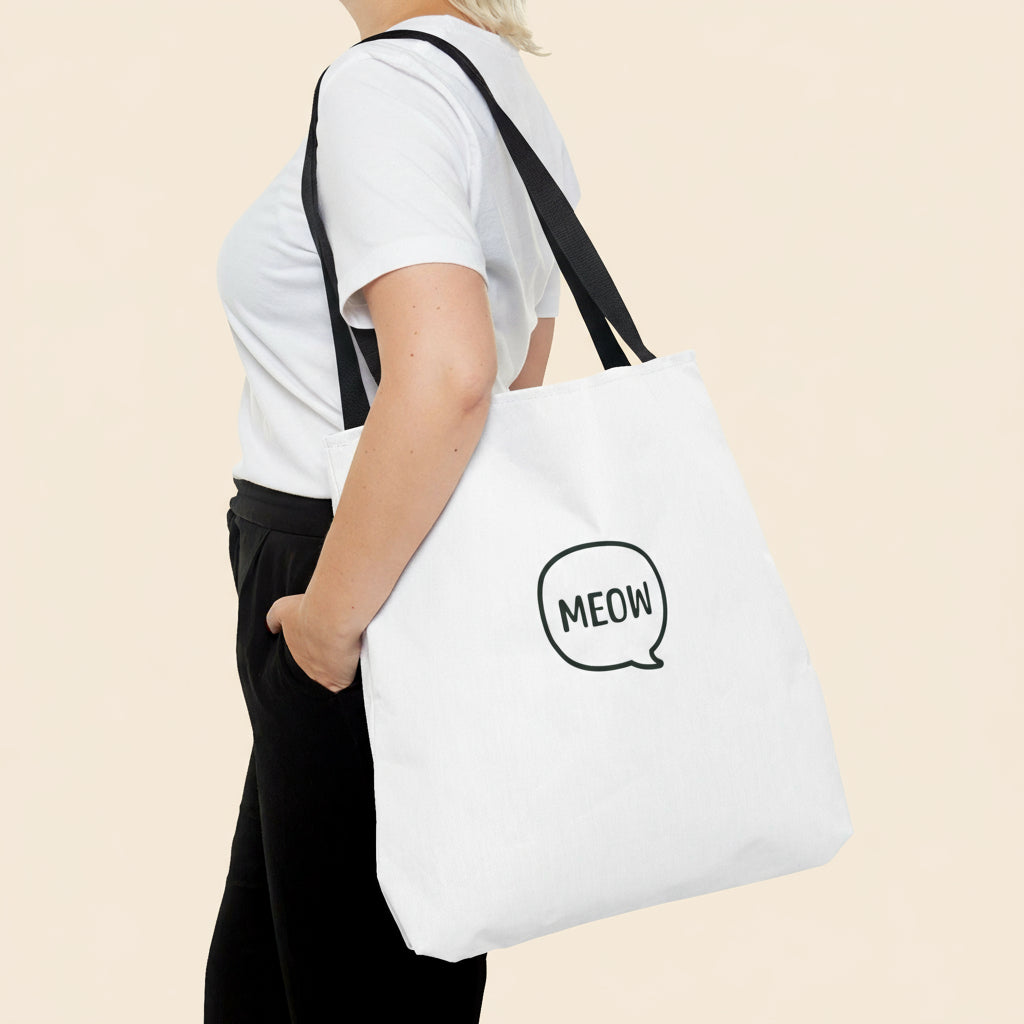 Person holding a white tote bag with 'MEOW' print on a white background