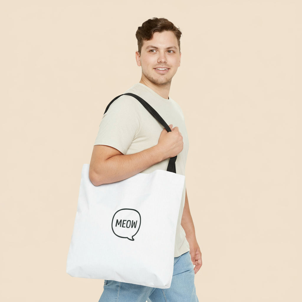 Man holding a white tote bag with 'MEOW' print on a tan background