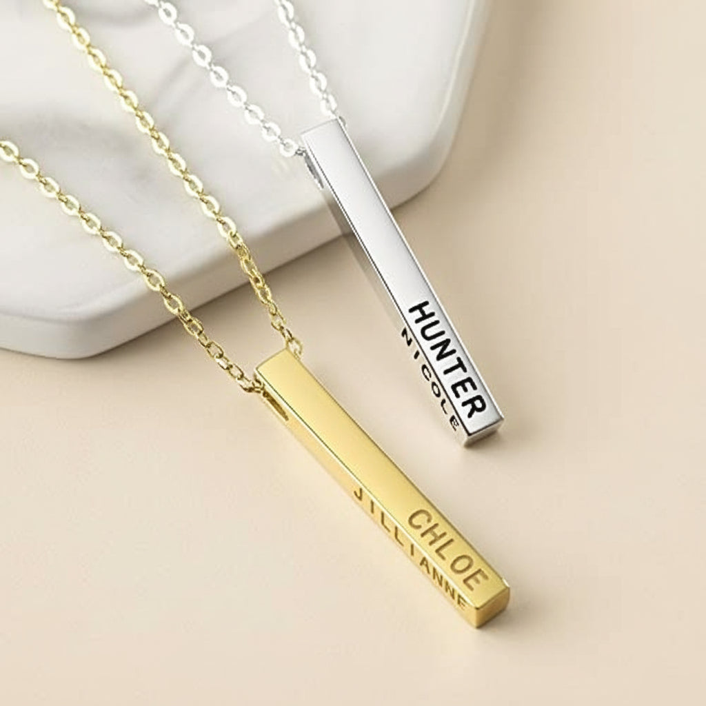 Two gold and silver bar necklaces with engraved names on a white background