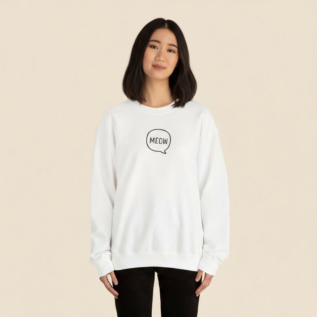 Person wearing a white sweatshirt with 'MEOW' print on a tan background