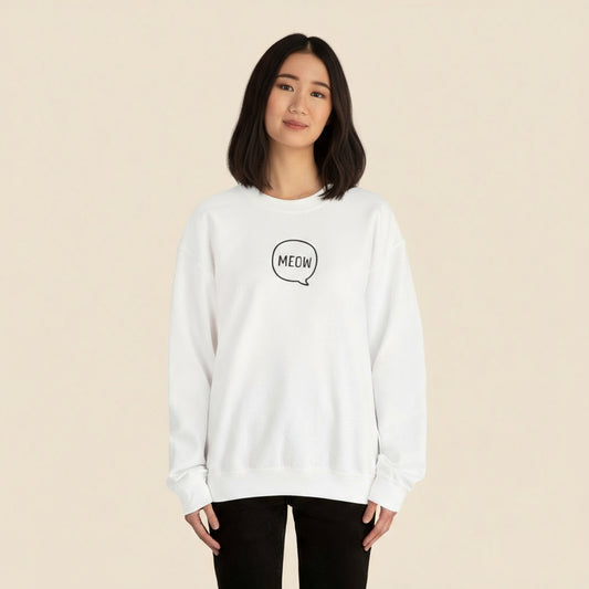 Person wearing a white sweatshirt with 'MEOW' print on a tan background