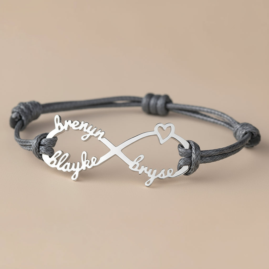 Bracelet with personalized names on an infinity symbol, displayed on a beige surface.