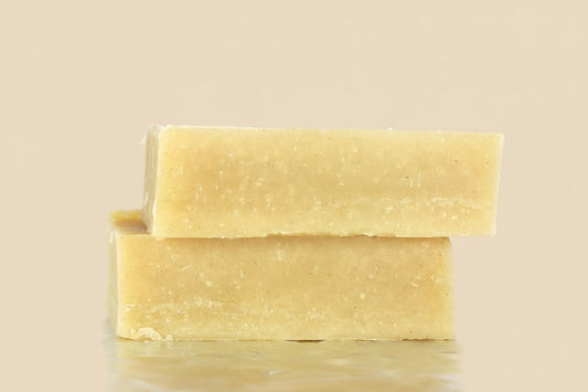 Two bars of yellow soap on a tan background