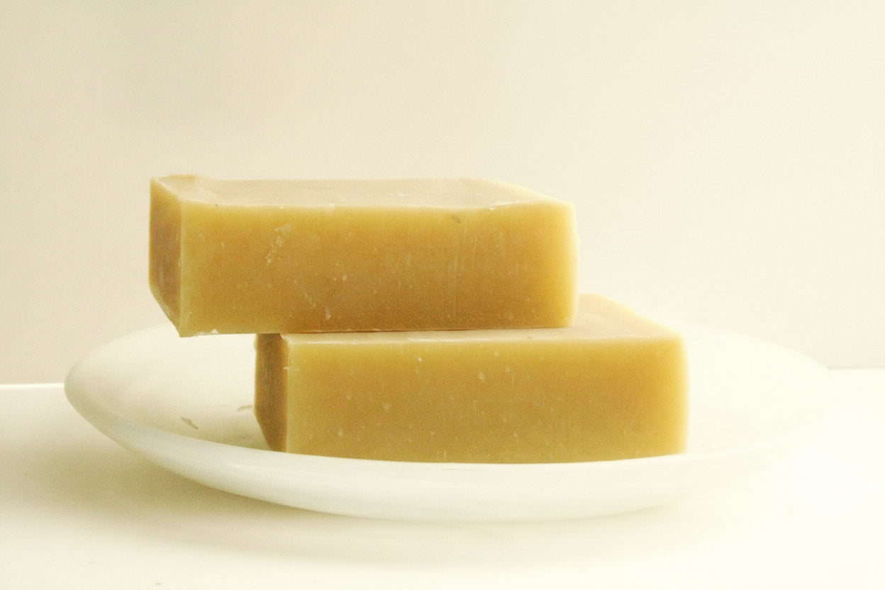 Two bars of soap on a white plate with a beige background