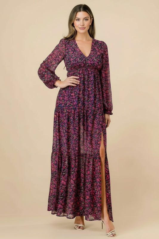 Woman wearing a long floral dress with a slit on a tan background