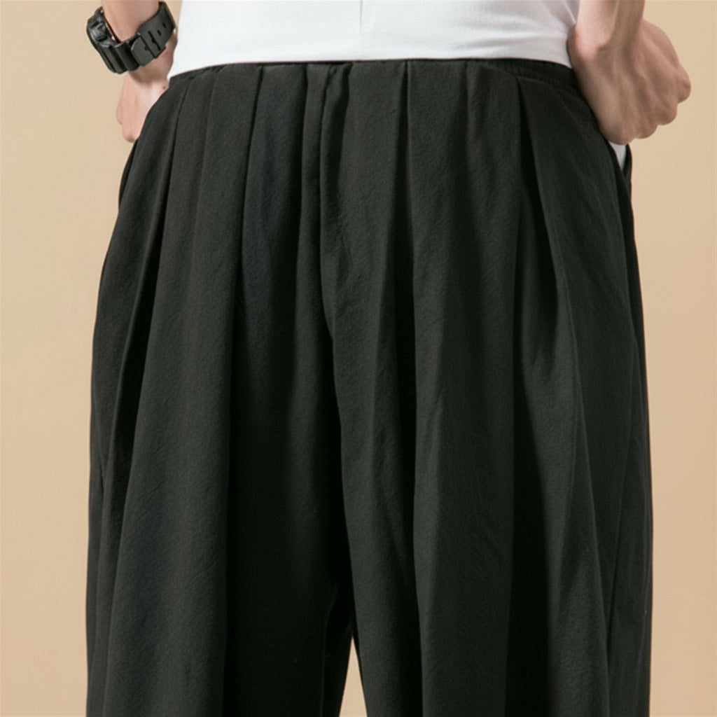 Black pleated pant worn by a person on a tan background