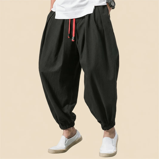 Black baggy pants with red drawstring on a white background, featuring the brand 'FGKKS'.