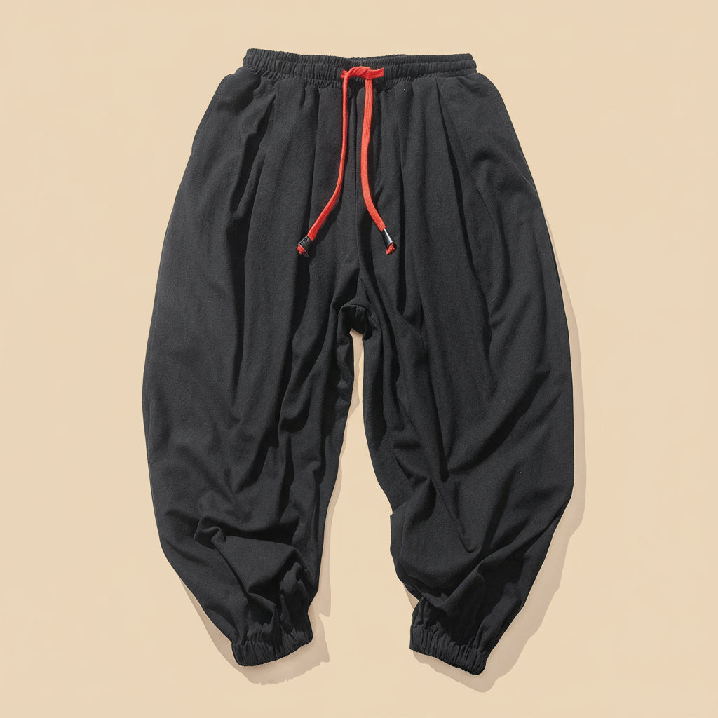 Black pants with red drawstring on a tan background