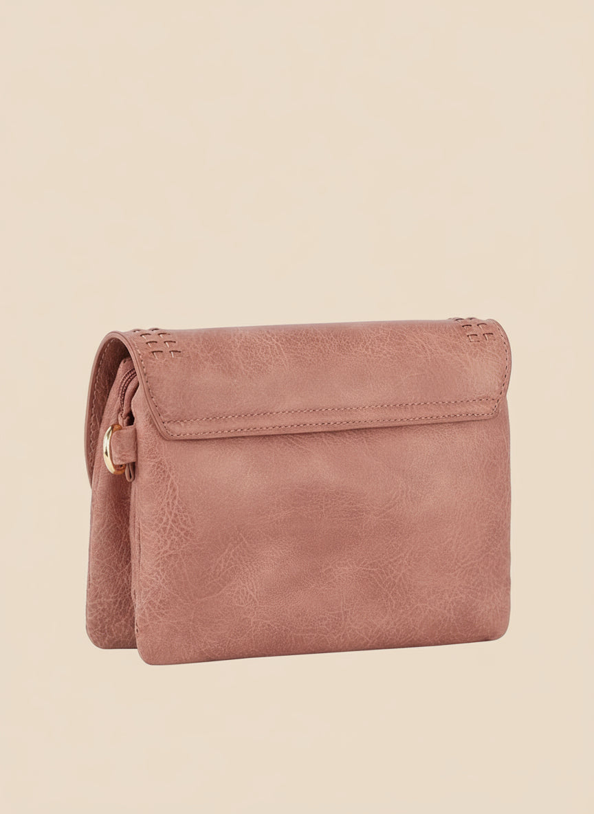 Pink leather crossbody bag on a tan background