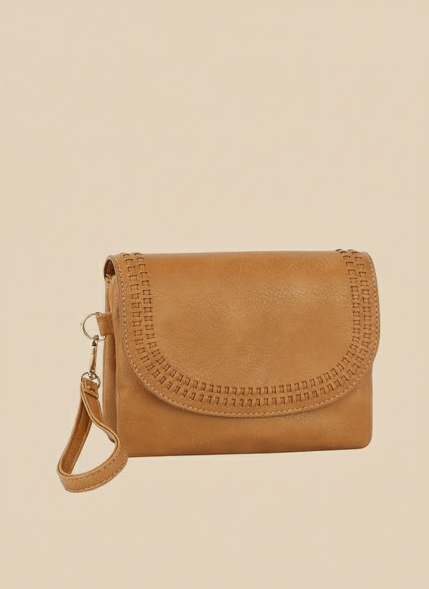 Tan leather handbag with decorative stitching on a beige background