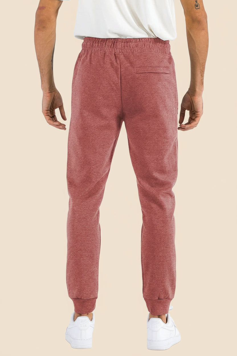 Person wearing red jogger pants on a tan background