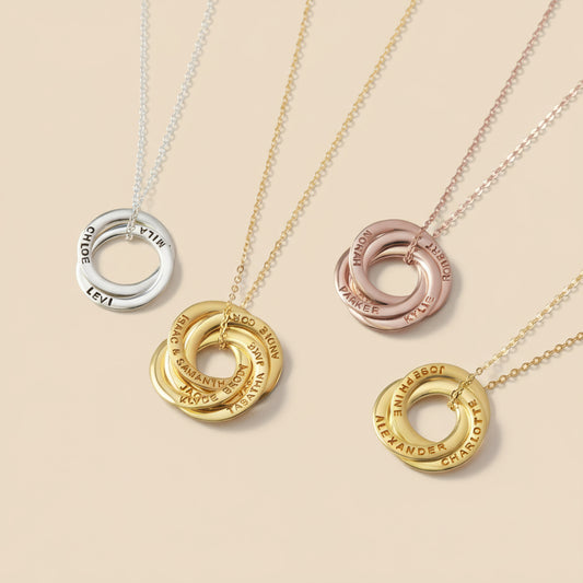 Four gold necklaces with interlocking rings on a light beige background