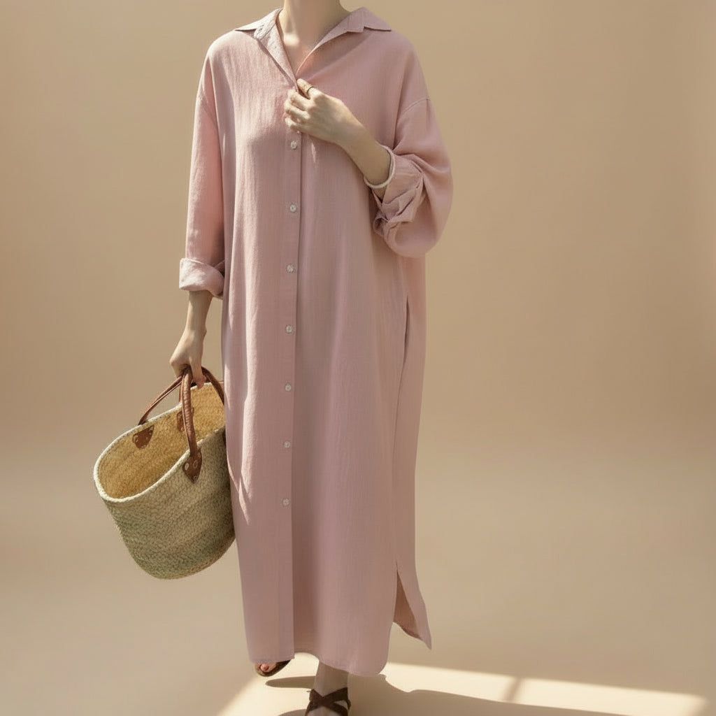 Person wearing a long pink dress holding a woven bag in front of tan background.