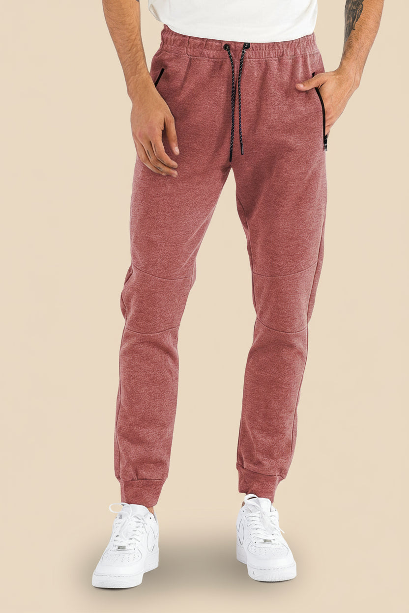 Person wearing maroon jogger pants and white sneakers on a tan background