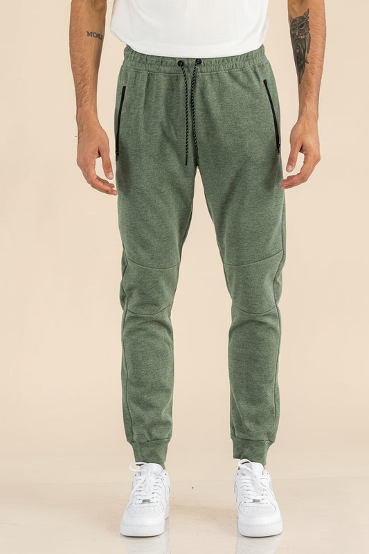 Person wearing green jogger pants and white sneakers on a white background