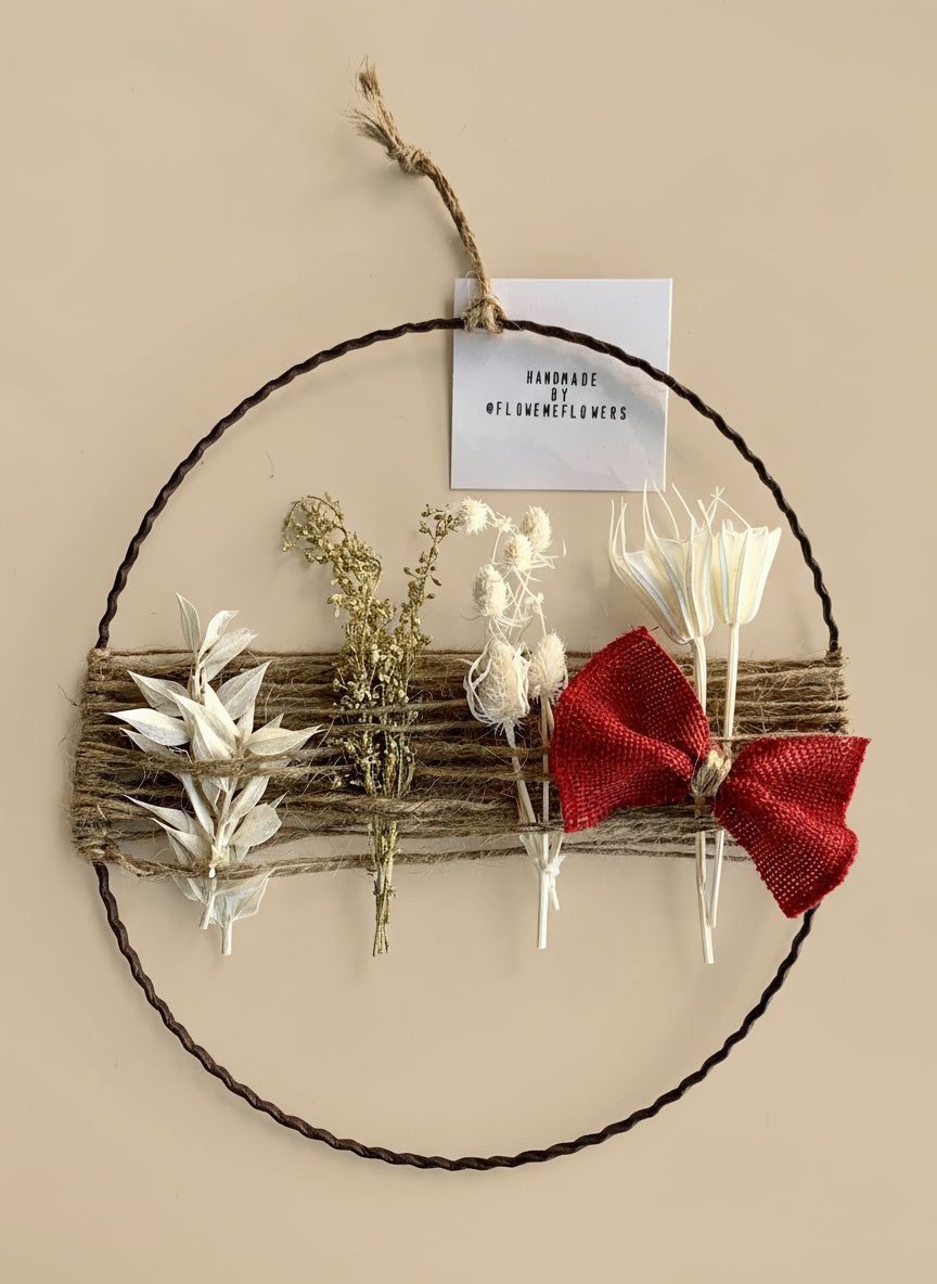 Decorative wreath with dried flowers and a red bow on a tan background