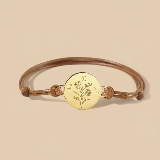 Bracelet with gold disc and floral engraving on a beige background