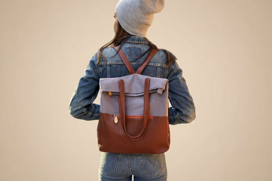 Person wearing a brown and gray backpack in front of tan background