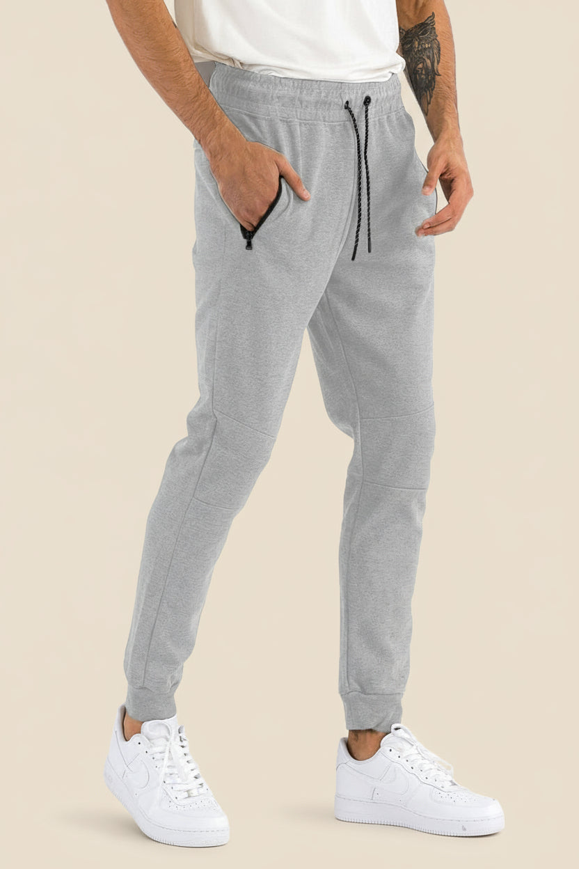 Person wearing gray jogger pants with a tan background