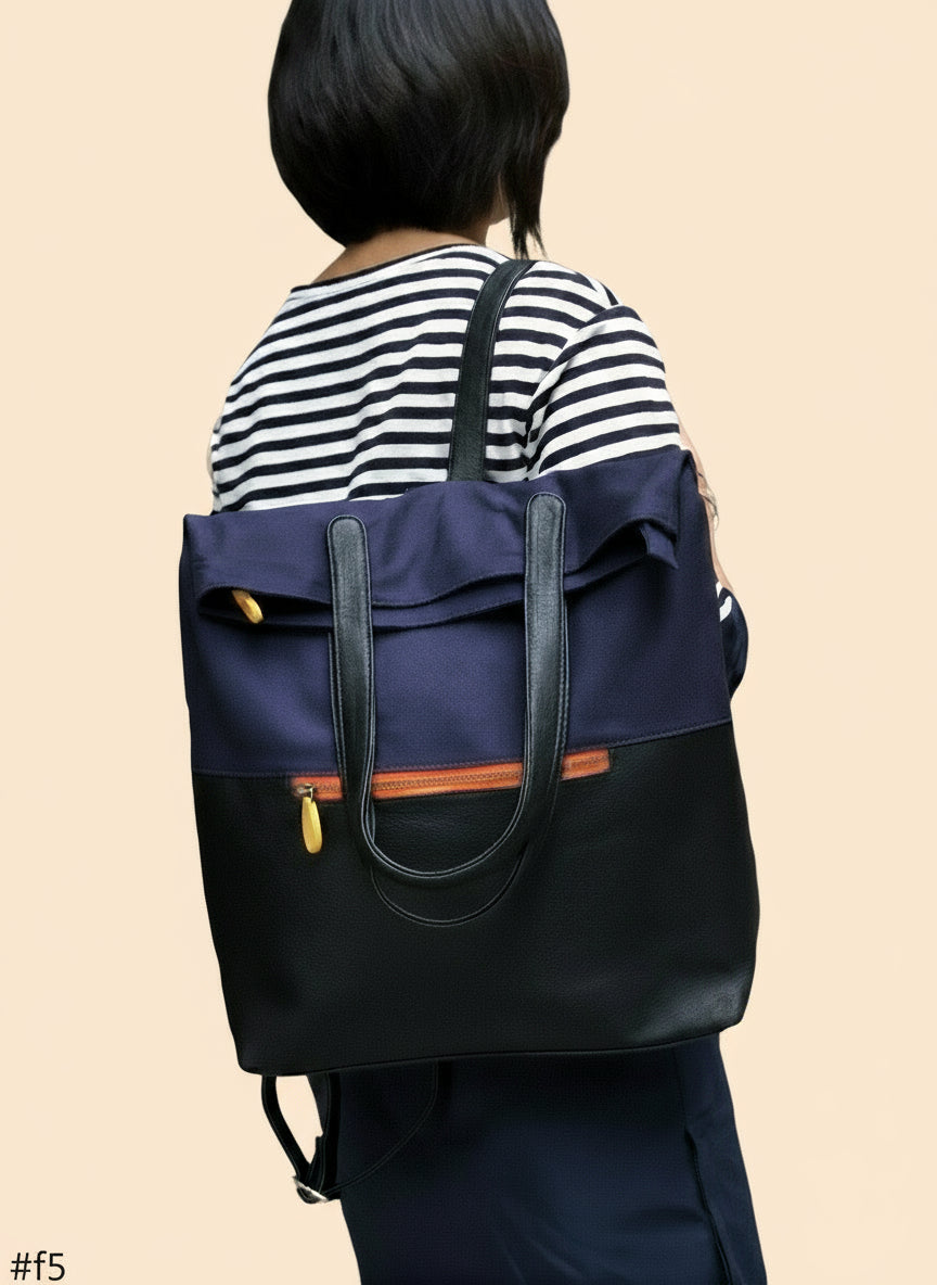 Person wearing a navy and black backpack with orange accents against a tan wall background