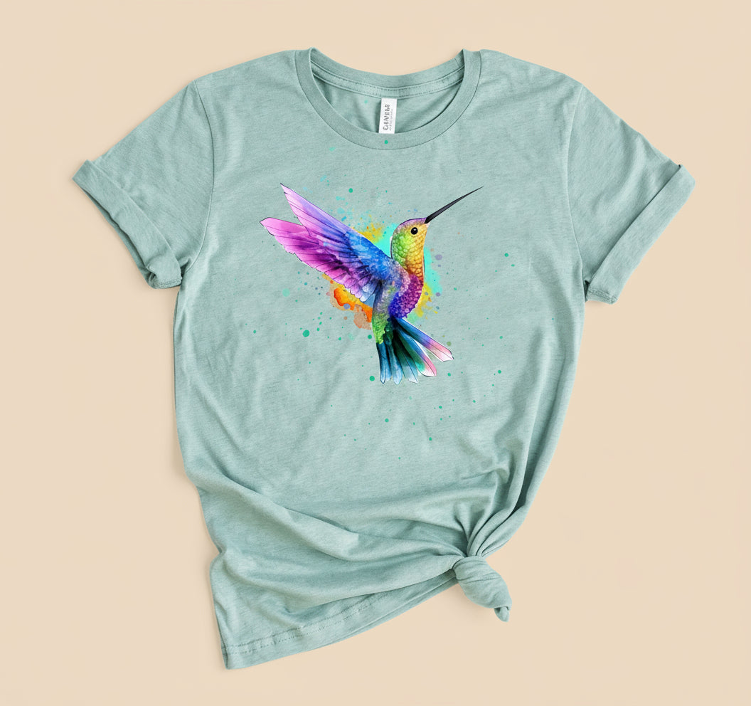 Mint green t-shirt with colorful hummingbird design, on a tan background.