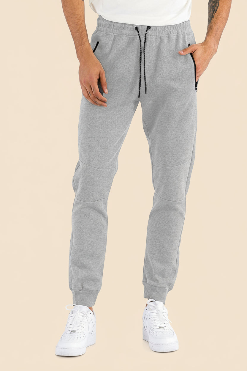 Gray jogger pants worn by a person on a tan background