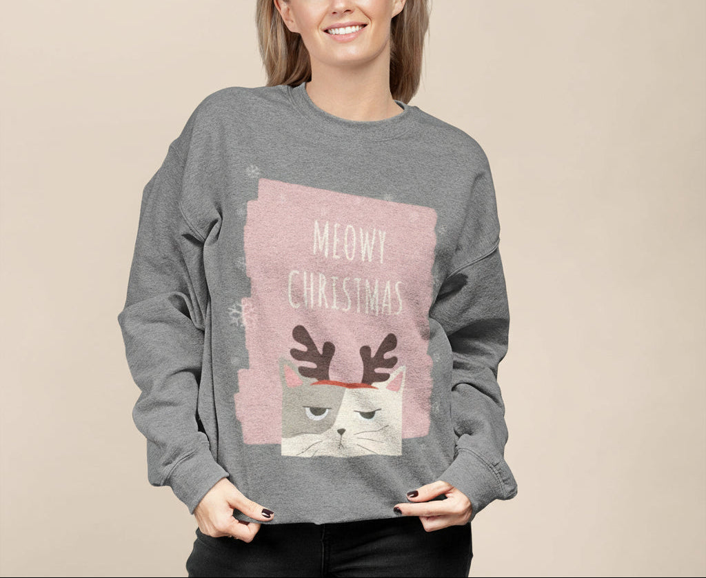 Person wearing a gray sweatshirt with a Christmas design featuring a cat and text on a plain background