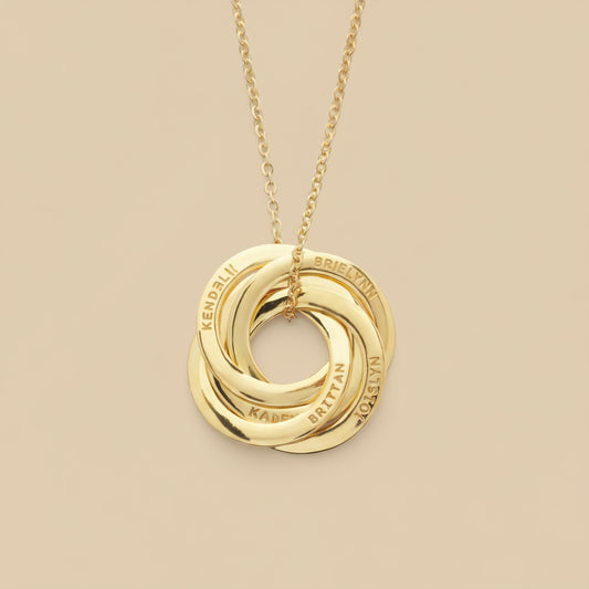 Gold necklace with interlocking rings on a light tan background