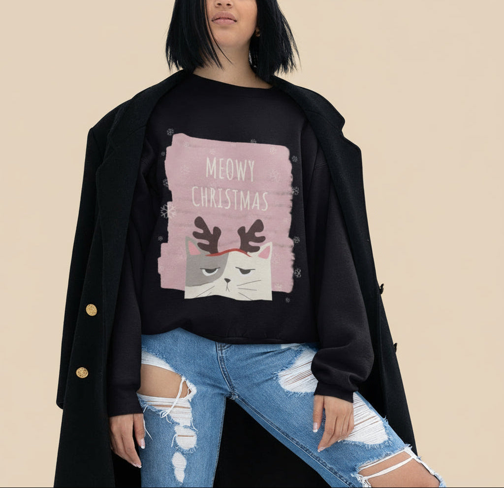 Person wearing a black sweater with a cat graphic and 'Meowy Christmas' text, standing against a tan background.