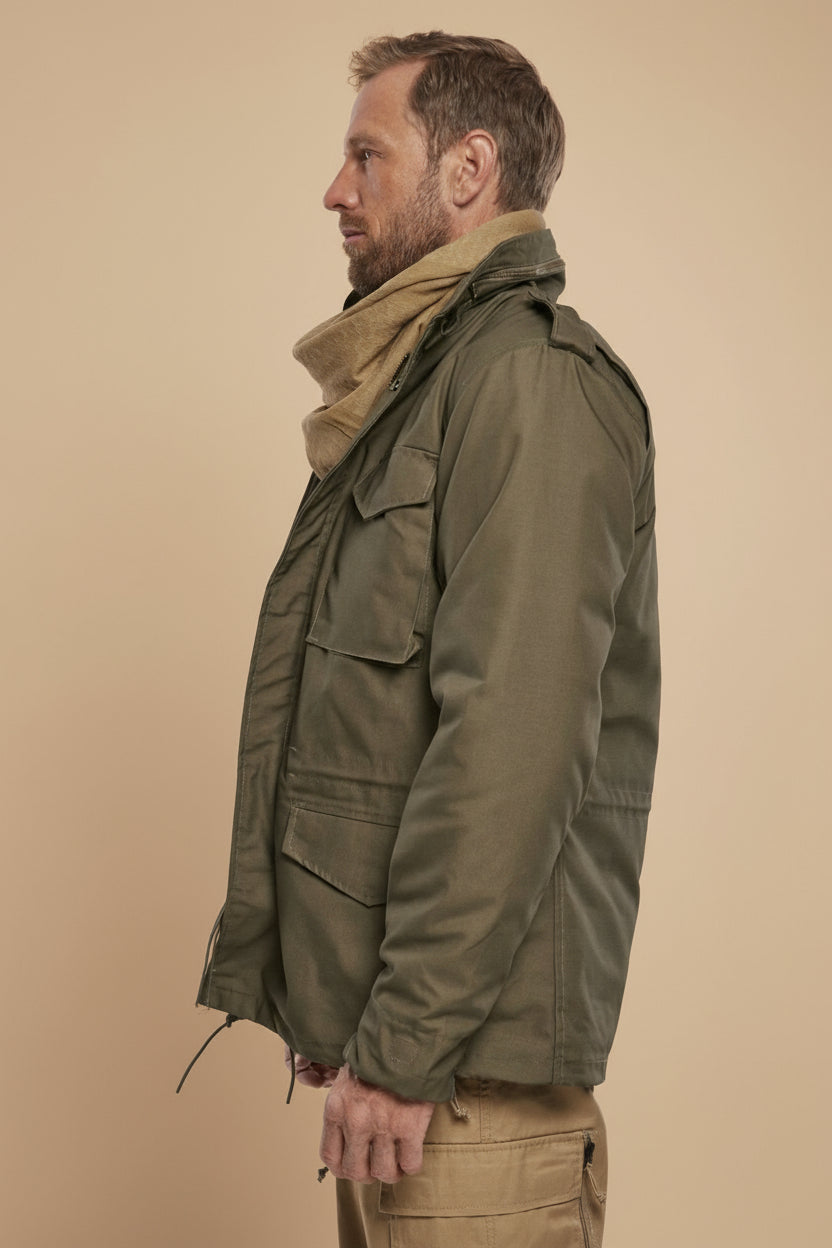 Man wearing a green jacket and beige scarf on a tan background