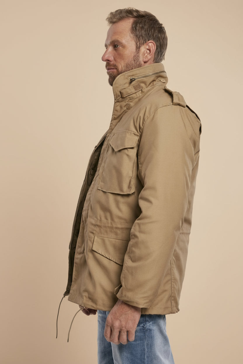 Man wearing a beige parka jacket on a tan background