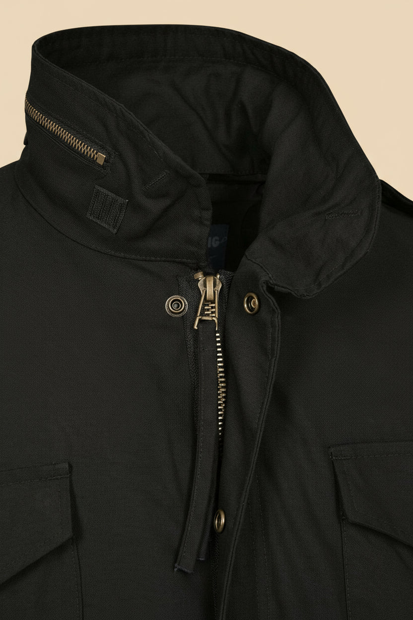 Close-up of a black jacket with a zipper and button details on a tan background